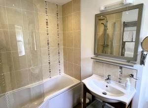 ein Badezimmer mit einem Waschbecken, einer Badewanne und einem Spiegel in der Unterkunft Ravenstone Lodge Country House Hotel in Keswick