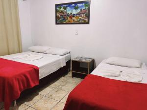 a room with two beds and a picture on the wall at Pousada da Maira in Foz do Iguaçu