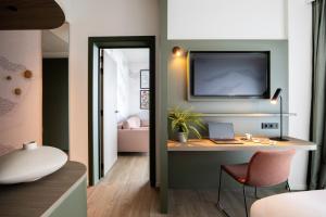 Zimmer mit einem Schreibtisch und einem TV an der Wand in der Unterkunft voco Brussels City North, an IHG Hotel in Vilvoorde