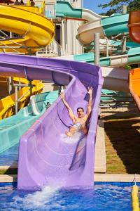 a man is sliding down a purple water slide at Gran Evenia Bijao - All Inclusive in Playa Blanca