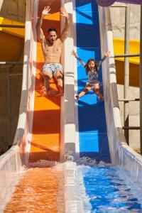 a man and a girl riding on a water slide at Gran Evenia Bijao - All Inclusive in Playa Blanca