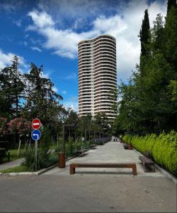 ein Park mit einer Bank und einem hohen Gebäude in der Unterkunft Tbilisi garden in Tbilisi City