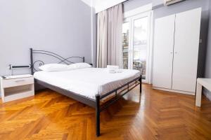 Egnatia Central Spacious 4 Bd Apt in Thessaloniki في سلانيك: غرفة نوم بيضاء مع سرير وأرضية خشبية