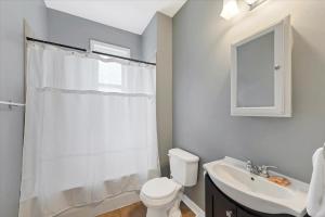 a white bathroom with a toilet and a sink at Historic First Floor Unit in STL - 5 Bedrooms in Soulard