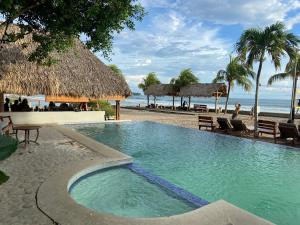 a swimming pool next to a beach with palm trees at Hacienda Iguana Cesars Colarado in Tola