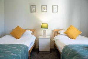 a bedroom with two beds and a lamp on a night stand at Barclay House Apartment in Fort William