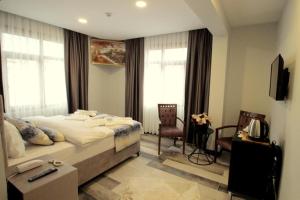 a bedroom with a bed and two chairs and a television at Güler Palas İstanbul Hotel in Istanbul
