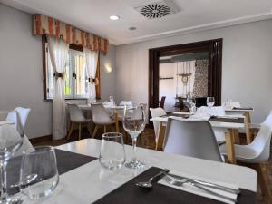un restaurante con mesas y sillas blancas y copas de vino en Hotel Santa Barbara, en Andorra