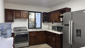 a kitchen with wooden cabinets and a stainless steel refrigerator at Termales la Montaña - Hot Springs in Ahuachapán