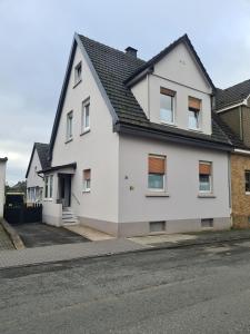 une maison blanche avec un toit noir dans une rue dans l'établissement Velbert am Berg, à Velbert