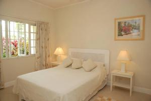 a bedroom with a white bed and a window at 26 Margate Gardens in Bridgetown