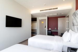 a hotel room with a bed and a flat screen tv at Thaya Hotel Bangkok in Bangkok