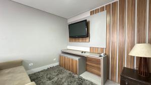 a hotel room with a television on a wall at 08- Studio perfeito para família! Aconchegante e novo! in Curitiba