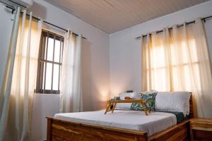 um quarto com uma cama e uma janela com cortinas em Le Nid des Lys em Lomé