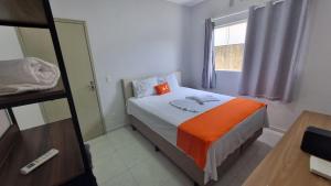 um quarto com uma cama com uma almofada laranja e uma janela em Achei Casa Seu Espaço Exclusivo no Condomínio Lagoa Azul Topazio em Porto Velho