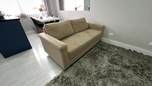 a couch sitting in a living room with a rug at 08- Studio perfeito para família! Aconchegante e novo! in Curitiba