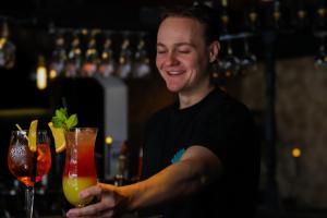 a man standing at a bar holding two cocktails at Hotel XL in Zandvoort