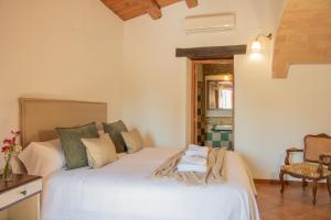 1 dormitorio con 1 cama blanca y 1 silla en Mas Camins, en Avinyonet de Puigventós