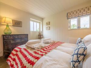 a bedroom with a large bed with a red and white blanket at Snow Hall Barn in Peasenhall