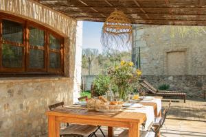 a wooden table with flowers on a patio at Mas Camins in Avinyonet de Puigventós