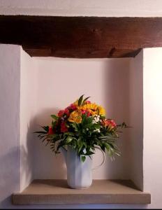 a bouquet of flowers in a white vase on a shelf at Ginevra Casa Vacanze in Panzano