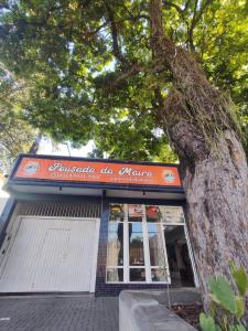 a tree in front of a building with a sign at Pousada da Maira in Foz do Iguaçu