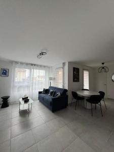 ein Wohnzimmer mit einem blauen Sofa und einem Tisch in der Unterkunft Appartement Plein Centre in Saint-Brevin-les-Pins