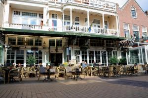 eine Außenterrasse mit Tischen und Stühlen vor einem Gebäude in der Unterkunft Hotel XL in Zandvoort