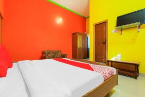 1 dormitorio con paredes de color naranja y amarillo y 1 cama en OYO Flagship 86687 Hotel Anandlok, en Haldwāni