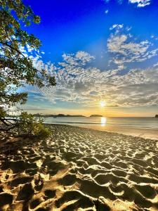 a sandy beach with the sun setting over the water at Apartamentos Tamarindo Guanacaste 3 in Guanacaste