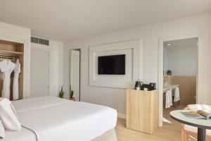 a white bedroom with a bed and a tv at Meliá Lloret de Mar in Lloret de Mar
