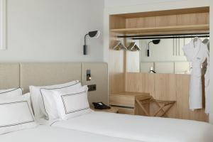 a bedroom with a bed with white pillows and a dress hanging up at Meliá Lloret de Mar in Lloret de Mar