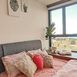 a bedroom with a bed with pink pillows and a window at 海景套房 3房3厕 可8-12人Danga Bay Country Garden YI JIA名宿 in Johor Bahru