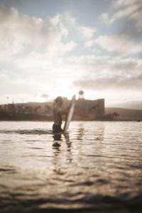 un joven sosteniendo un murciélago en el agua en La Ventana Azul Surf Hostel, en Las Palmas de Gran Canaria