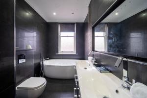 a bathroom with a tub and a toilet and a sink at Bannerdale Villa 5 bedroom in Nether Edge