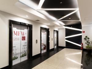 un couloir avec plusieurs portes en verre dans un bâtiment dans l'établissement Hotel Mega Polo, à São Paulo