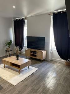 ein Wohnzimmer mit einem TV und einem Couchtisch in der Unterkunft L'appart Saint-Laurent in Chalon-sur-Saône