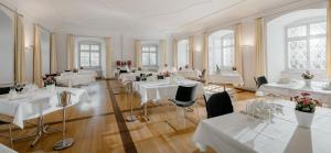 Hotel Kloster Fischingen في Fischingen: غرفة طعام مع طاولات وكراسي بيضاء