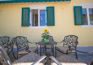 une terrasse avec des chaises, une table et un vase avec un tournesol dans l'établissement Landhaus Gretl by S4Y, à Krumpendorf am Wörthersee