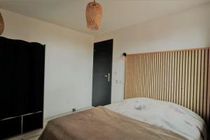 1 dormitorio con 1 cama y pared de madera en Pied à terre central Pays Basque, en Larressore
