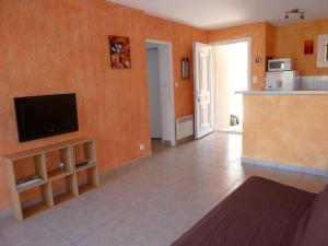 普羅普里亞諾的住宿－T3 en rdj pour 6 pers dans résidence avec piscine，客厅配有一台位于橙色墙壁上的平面电视。