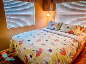 a bedroom with a bed with a colorful comforter and a window at Pinecraft Cottage Tiny Home in Sarasota