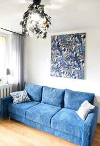 a blue couch in a living room with a chandelier at Apartament 55 in Węgierska Górka