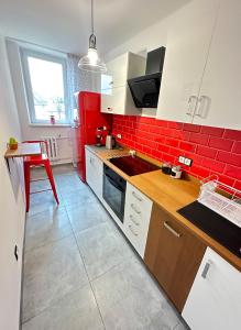 a kitchen with red walls and white cabinets and a table at Apartament 55 in Węgierska Górka