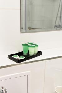 a tray with three green cups on a bathroom counter at Apartament 55 in Węgierska Górka