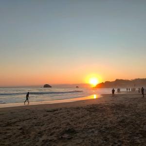 a group of people walking on the beach at sunset at Hostal Ledeztrus in Zipolite