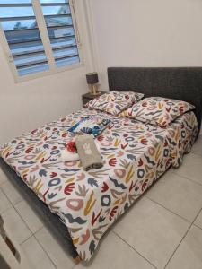 Una cama con edredón y una almohada. en An'Kanna en Petit-Bourg