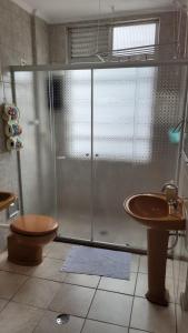 a bathroom with a shower and a toilet and a sink at Frente Mar - Apartamento para 4 Hóspedes com Home Office Wi-Fi 200mbps, Ar Condicionado e Cozinha Completa in São Vicente