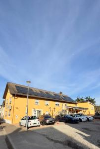 a yellow building with cars parked in a parking lot at Europa Pension zum Grünen Baum in Rust