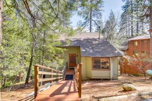 Una pequeña casa amarilla con un porche de madera en el bosque en Arnold Cabin with Hot Tub and Community Lake Access!, en Arnold